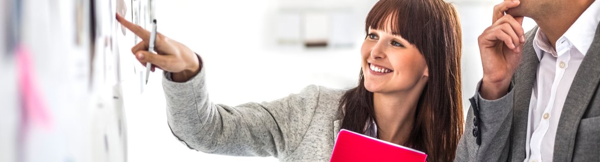 Young businesswoman with male colleague brainstorming at board in office